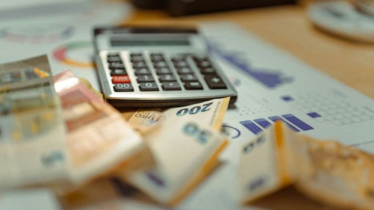 Calculator sitting on top of a pile of banknotes and receipts