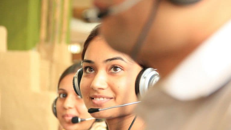 Two customer support agents wearing headsets in a bright office
